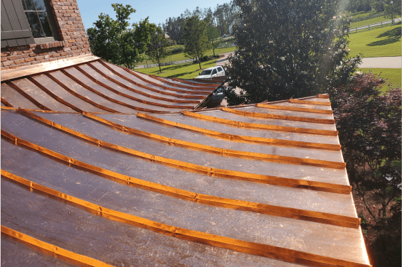 Close up of a copper roof with a neighborhood in the background