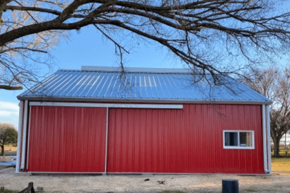 The side of a red barn with a metal roof